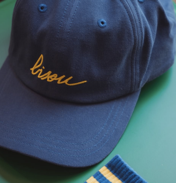 Casquette unisexe « Bisou » bleu foncé avec broderie jaune, réglable et fabriquée en coton, pour un style tendance et pratique.