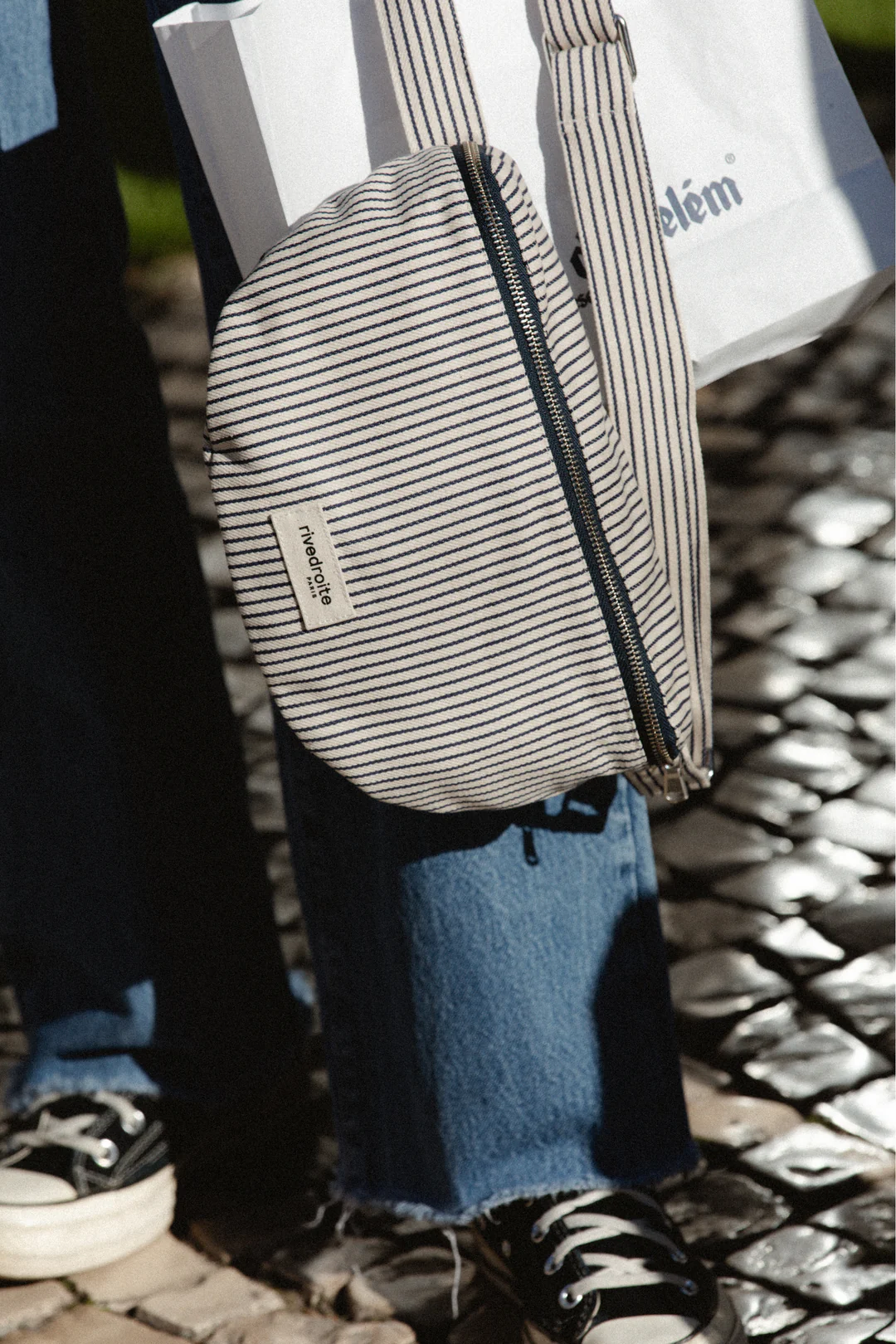 Sac banane Custine rayé bleu marine et blanc en coton recyclé et organique, avec anse ajustable et zip argenté.