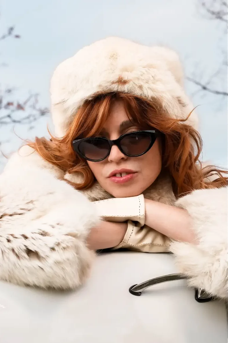 Lunettes de soleil noires rétro JADE de IYU DESIGN portées par une femme élégante en extérieur