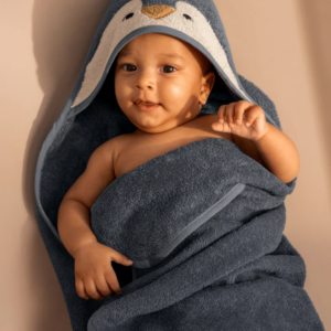 Bébé enveloppé dans une serviette de bain bleue à capuche pingouin en coton biologique GOTS