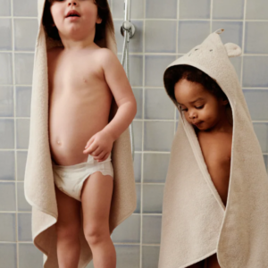 Bébé enveloppé dans une serviette à capuche en coton biologique ALBERT, idéale pour la sortie de bain