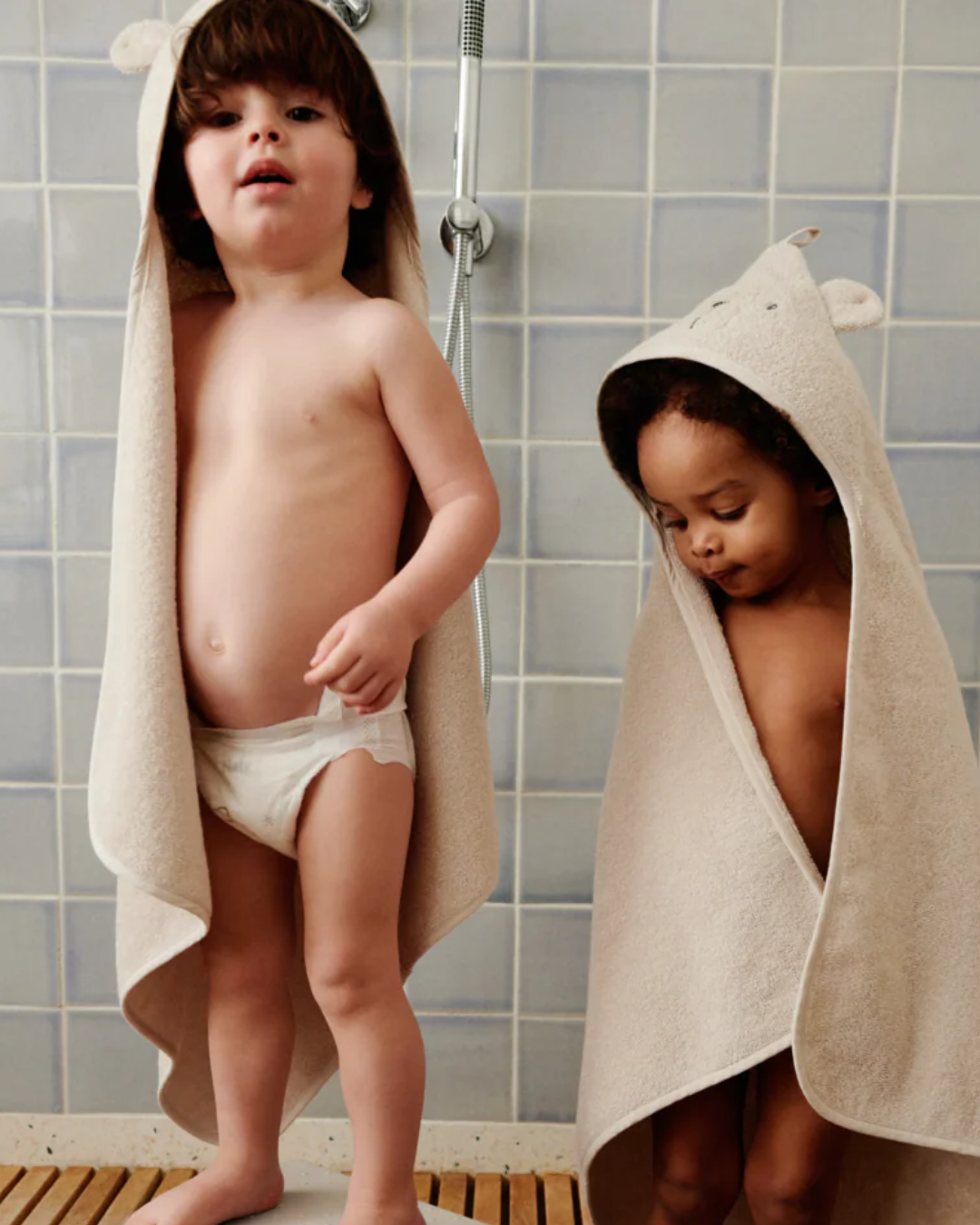 Bébé enveloppé dans une serviette à capuche en coton biologique ALBERT, idéale pour la sortie de bain