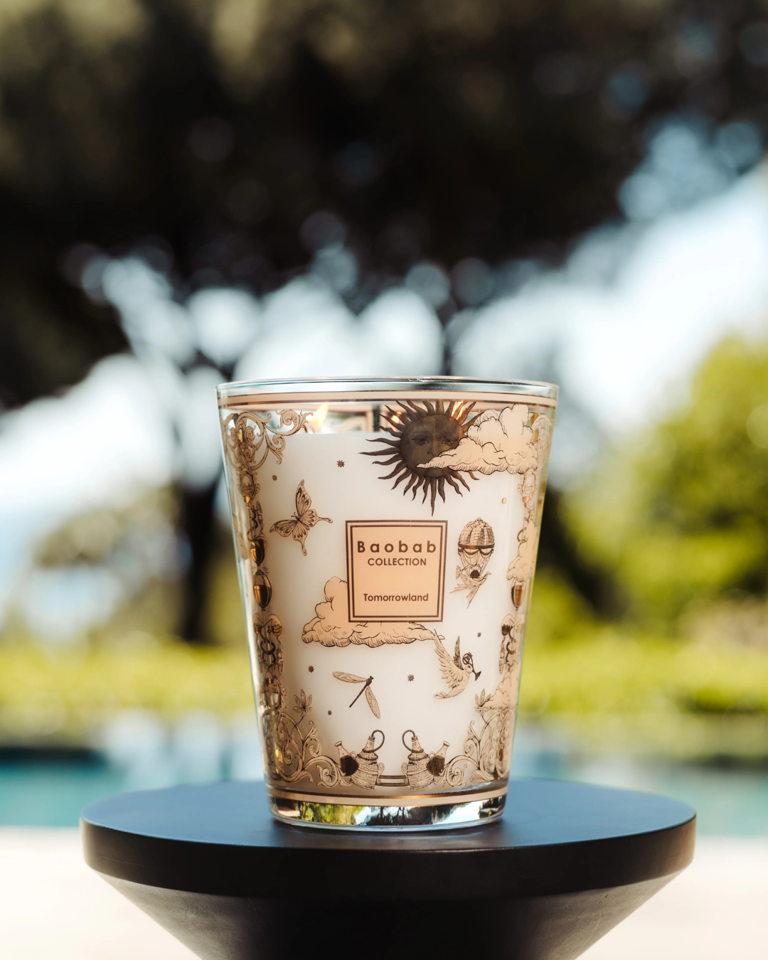 Bougie parfumée Baobab Tomorrowland Max 24 décor or et noir avec papillons et montgolfières.