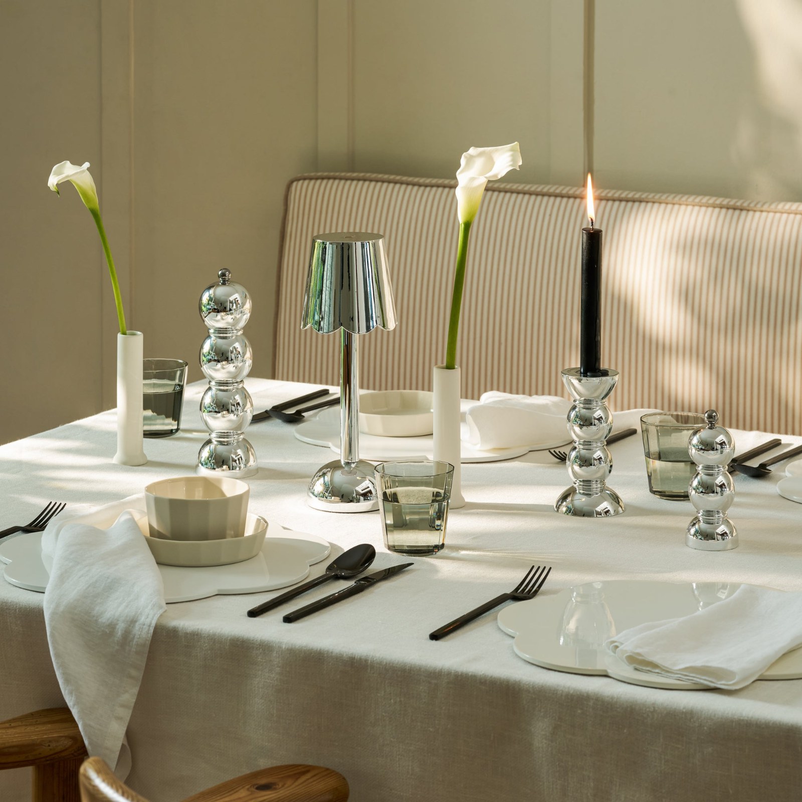 Table dressée avec nappe blanche, bougeoirs Bobbin Chrome Addison Ross, bougies et soliflores