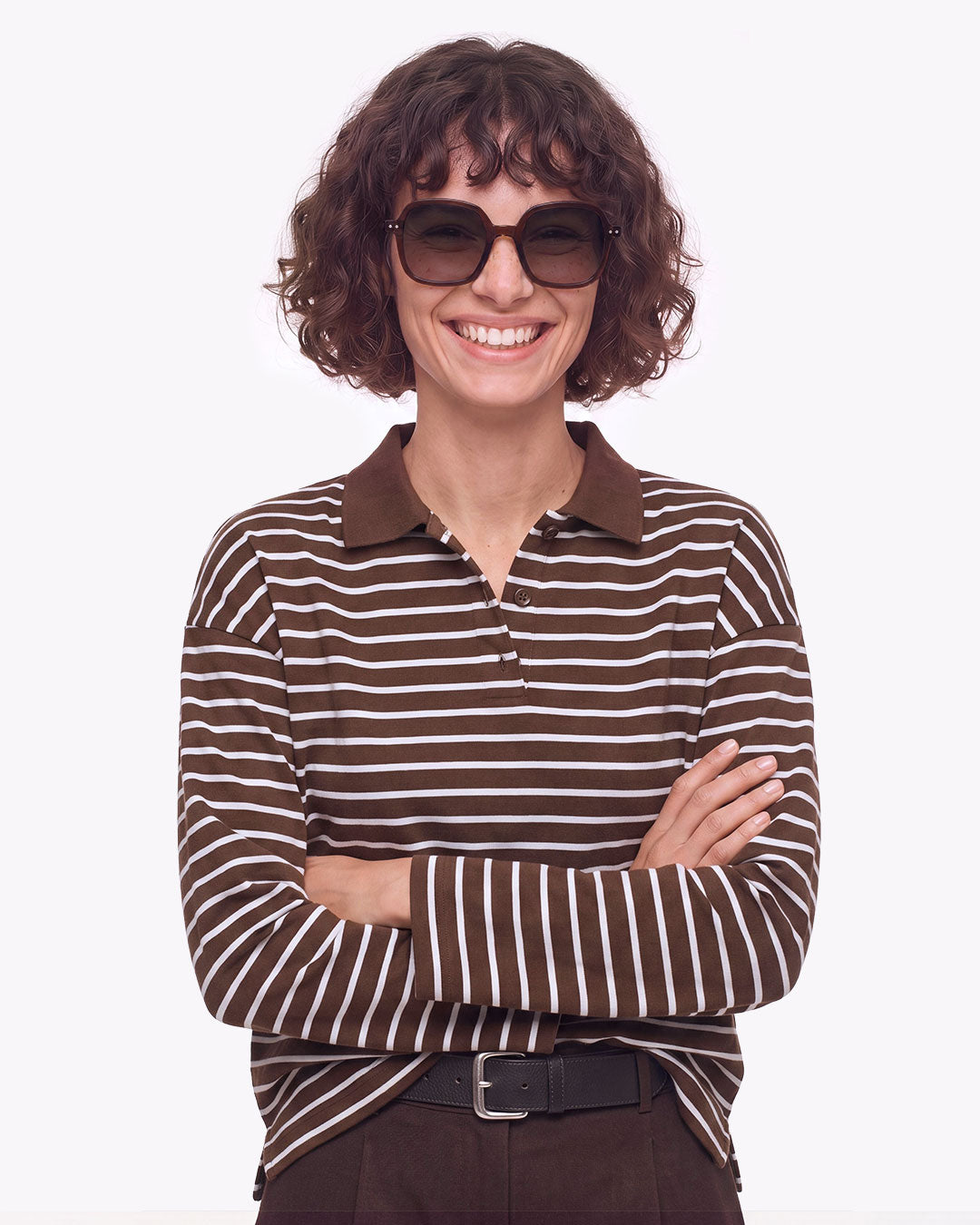 Femme aux cheveux bouclés en haut rayé, bras croisés, portant les lunettes de soleil oversize Izipizi OFFICE Dark Expresso