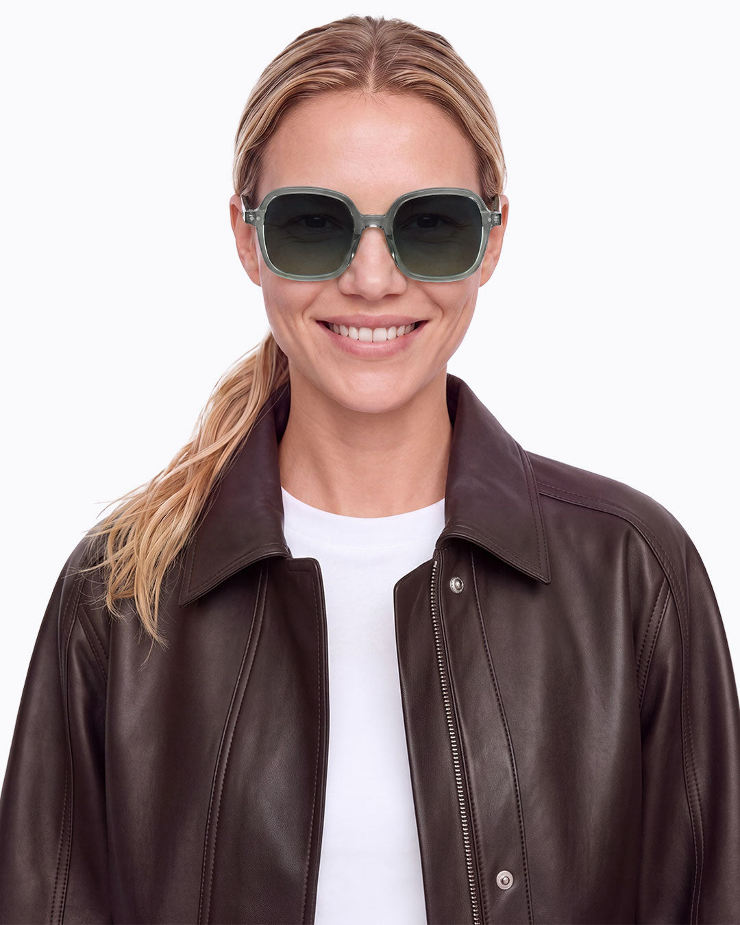 Femme blonde souriante en veste en cuir marron portant les lunettes de soleil oversize Izipizi OFFICE Station Seat