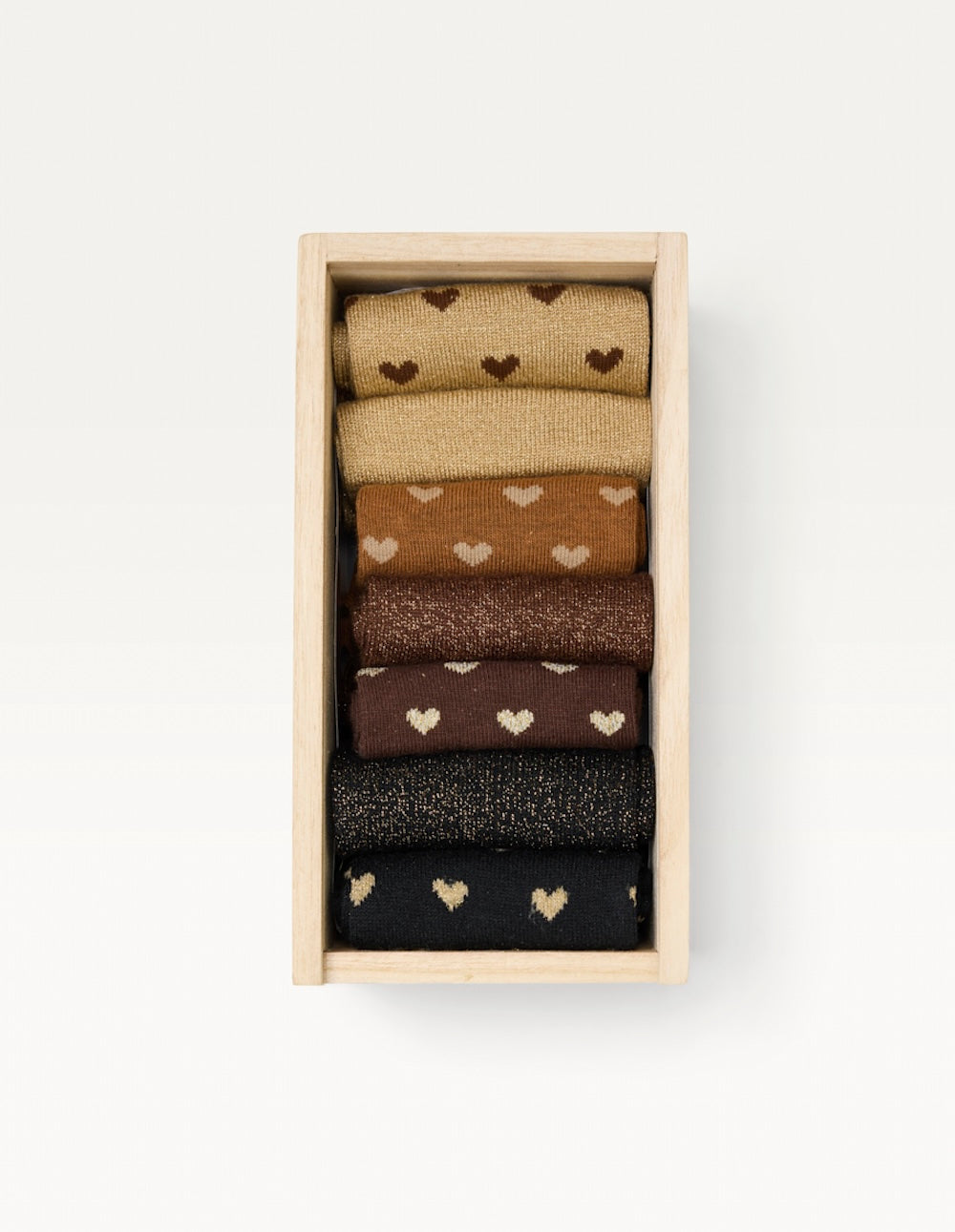 Coffret en bois clair vu de dessus contenant les sept paires de chaussettes cœur et paillettes Odaje roulées